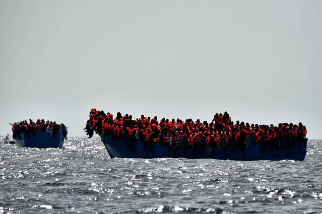 Migrants wait to be rescued as they drift in the Mediterranean Sea some 20 nautical miles north off the coast of Libya on October 3, 2016. Italy coordinated the rescue of more than 5,600 migrants off Libya, three years to the day after 366 people died in a sinking that first alerted the world to the Mediterranean migrant crisis. (Photo by Aris Messinis/AFP Photo)