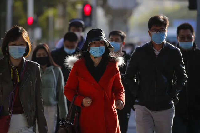 Pedestrians wearing face masks to help curb the spread of the coronavirus walk on a street during the morning rush hour in Beijing, Wednesday, October 21, 2020. (Photo by Andy Wong/AP Photo)