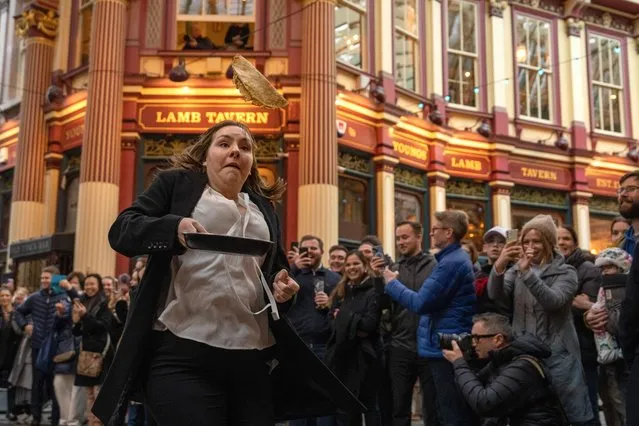 A woman takes part in a pancake race in Leadenhall Market on February 21, 2023 in London, England. Hosted by the Lamb Tavern, an 18th century pub in the centre of the Victorian market, the race is held annually on Shrove Tuesday. (Photo by Carl Court/Getty Images)