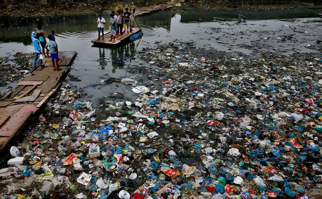 A man guides a raft through a polluted canal littered with plastic bags and other garbage in Mumbai, India, Sunday, October 2, 2016. (Photo by Rafiq Maqbool/AP Photo)