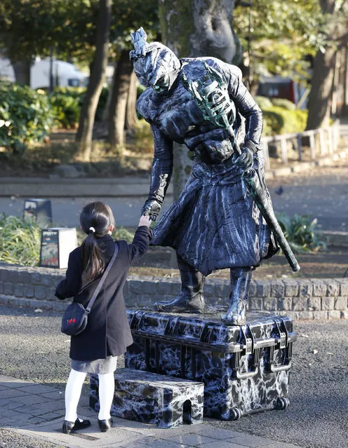 Street performer Bold Yamada shakes hands with a child at a park in Tokyo, Monday, December 22, 2014. (Photo by Shizuo Kambayashi/AP Photo)