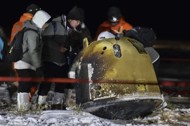 In this photo released by Xinhua News Agency, recovery crew members check on the capsule of the Chang'e 5 probe after its successful landed in Siziwang district, north China's Inner Mongolia Autonomous Region on Thursday, December 17, 2020. A Chinese lunar capsule returned to Earth on Thursday with the first fresh samples of rock and debris from the moon in more than 40 years. (Photo by Ren Junchuan/Xinhua via AP Photo)