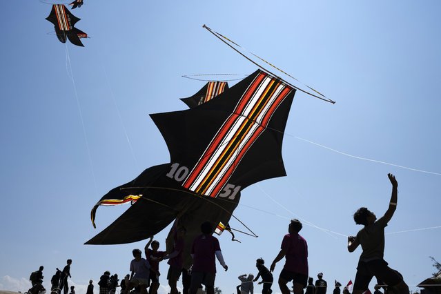 People fly kites during a traditional kite festival in Denpasar, Bali, Indonesia, 29 June 2024. The Bali Kite Festival is not just a competition but also a significant religious event for the Balinese people. It is believed that flying kites during this festival helps to send messages to the Hindu gods, asking for abundant harvests and warding off evil spirits. Balinese kites come in various shapes, sizes, and designs. The most common traditional design is the “Bebean” kite, which has a fish-like shape. Other popular designs include the “Janggan”, bird-shaped kite and “Pecukan”, leaf-shaped kite. Kite-flying in Bali is often a team effort, with groups of people working together to fly and control the kites. The festival typically takes place during the windy season, which is from June to August. (Photo by Made Nagi/EPA)