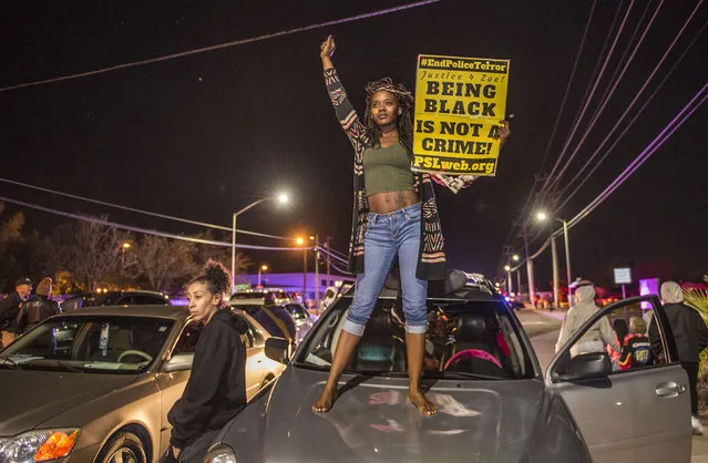 Kianshay Brown of Sacramento stands on a car on Meadoview Rd. as she joined participants of a candlelight vigil in honor of Stephon Clark who marched to the area near where Clark was shot at his grandparents home in Sacramento, Calif., on March 23, 2018. (Photo by Hector Amezcua/Sacramento Bee via ZUMA Wire)