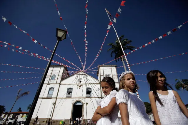 Girls representing angels stand in front of Our Lady of the Rosary church, during the “Cavalhadas” festival, in Pirenopolis, Brazil, Sunday, May 19, 2013. The popular festival is a tradition that was introduced in the 1800's by a Portuguese priest to mark the the ascension of Christ. The 3-day festival reenacts the Christian knights' defeat of the Moors. (Photo by Eraldo Peres/AP Photo)