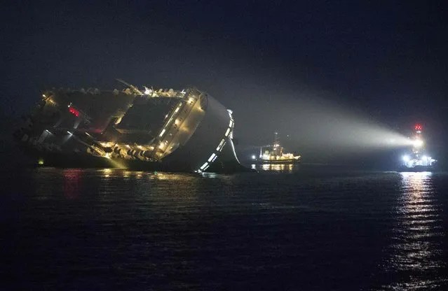 A tug illumnates the cargo ship Hoegh Osaka as it lies on its side after running aground on Saturday evening in the Solent estuary, near Southampton in southern England, January 4, 2015. (Photo by Peter Nicholls/Reuters)