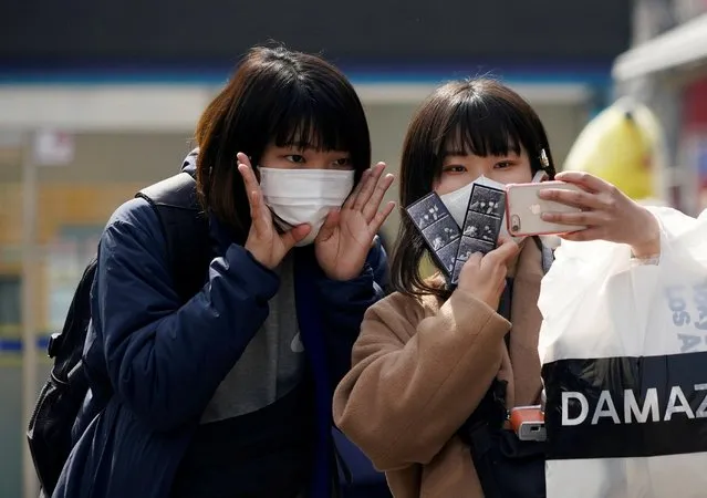 Tourists wearing masks to prevent the coronavirus take a selfie at a shopping district in Seoul, South Korea, February 24, 2020. (Photo by Kim Hong-Ji/Reuters)
