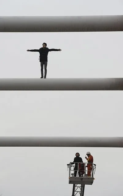 A man spreads his arms after climbing onto the top of a bridge in an attempt to commit suicide as rescuers (bottom) mediate with him from a scaling ladder, in Liuzhou, Guangxi Zhuang Autonomous Region January 9, 2015. (Photo by Reuters/Stringer)