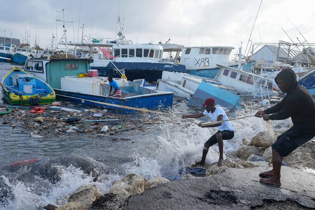 Fishermen pull a boat damaged by Hurricane Beryl back to the dock at the Bridgetown Fisheries in Barbados, Monday, July 1, 2024. (Photo by Ricardo Mazalan/AP Photo)