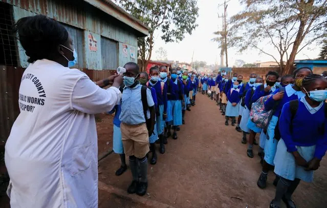 A worker checks the temperature of schoolchildren before entering the Olympic Primary School during the reopening of schools, after the government closed learning institutions due to the coronavirus disease (COVID-19) outbreak, in Kibera slums of Nairobi, Kenya January 4, 2021. (Photo by Thomas Mukoya/Reuters)