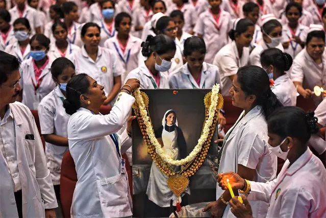 Indian nurses put a garland on a portrait of Florence Nightingale, the founder of modern nursing, to mark her birth anniversary on International Nurses Day, at the Government Kilpauk Medical College in Chennai, India, 12 May 2023. International Nurses Day is observed every year on 12 May to commemorate the birthday of Florence Nightingale and to honor nurses across the world for their contribution to the medical sector. (Photo by Idrees Mohammed/EPA)