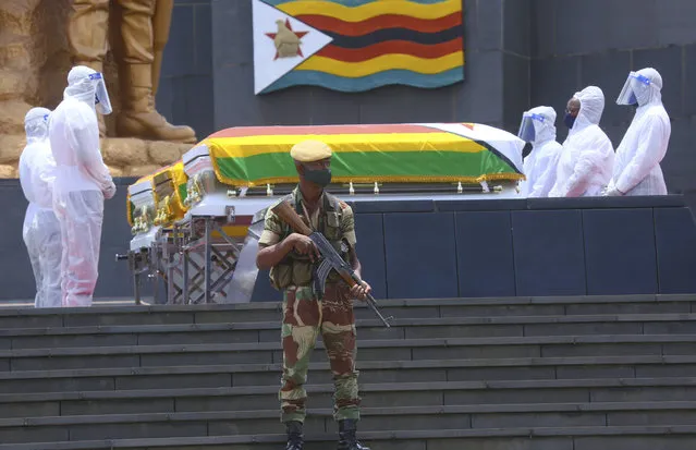 Pallbearers stand next to the coffins of three top government officials prior to their burial, at the National Heroes Acre in Harare, Wednesday, January 27, 2021. Zimbabwe on Wednesday buried three top officials who succumbed to COVID-19, in a single ceremony at a shrine reserved almost exclusively for the ruling elite as a virulent second wave of the coronavirus takes a devastating toll on the country. (Photo by Tsvangirayi Mukwazhi/AP Photo)
