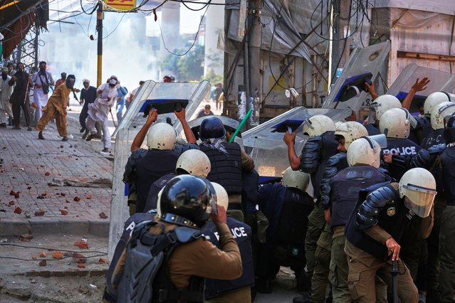 Supporters of Islamist party 'Tehreek-e-Labbaik Pakistan' throw stones toward police who take cover behind shields during clashes ahead of their pro-Palestinian march toward capital Islamabad, in Lahore, Pakistan, Friday, October 10, 2025. (Photo by K.M. Chaudary/AP Photo)
