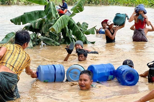 Residents wade through high flood waters in Pyinmana in Myanmar's Naypyidaw region on September 13, 2024, following heavy rains in the aftermath of Typhoon Yagi. Typhoon Yagi brought a colossal deluge of rain that has inundated a swathe of northern Vietnam, Laos, Thailand and Myanmar, triggering deadly landslides and widespread river flooding. (Photo by Sai Aung Main/AFP Photo)