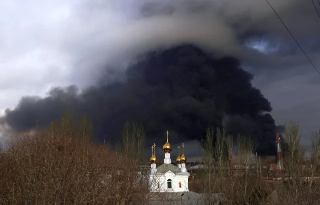 An Orthodox Church is seen in front an oil refinery which caught fire following a missile attack near the port city of Odesa, amid the ongoing Russia's invasion, in Ukraine, April 3, 2022. (Photo by Nacho Doce/Reuters)