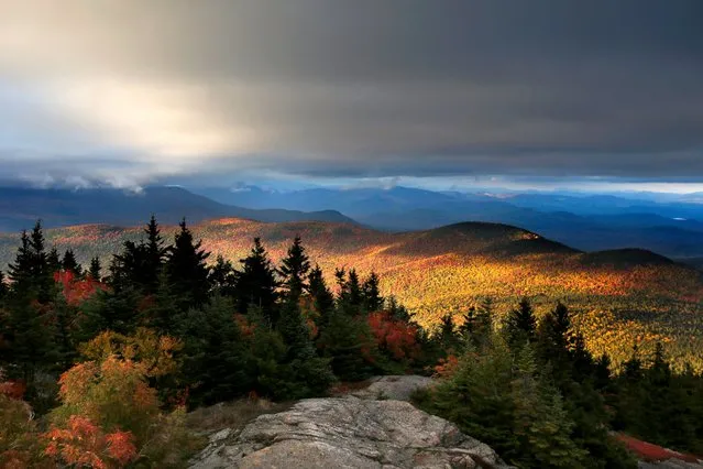 Fall foliage colors a line of mountains in Chatham, N. H., as unsettled weather begins to clear, October 4, 2016. The state's mountain regions are approaching their peak autumn colors. (Photo by Robert F. Bukaty/AP Photo)