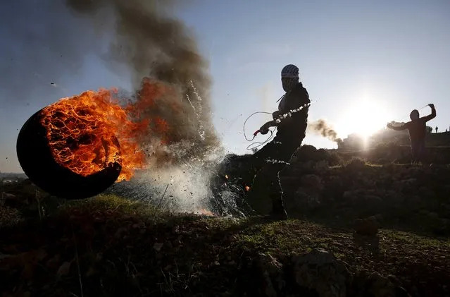 A Palestinian protester kicks a burning tyre during clashes with Israeli troops, near Israel's Ofer Prison near the West Bank city of Ramallah December 25, 2015. (Photo by Mohamad Torokman/Reuters)