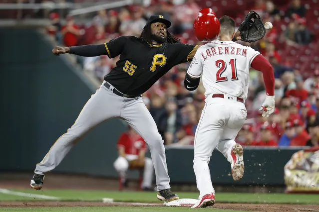 Pittsburgh Pirates first baseman Josh Bell misses the ball on the throw from starting pitcher Nick Kingham to allow Cincinnati Reds' Michael Lorenzen to reach first safely in the fifth inning of a baseball game, Saturday, July 21, 2018, in Cincinnati. Lorenzen was charged with a throwing error. (Photo by John Minchillo/AP Photo)