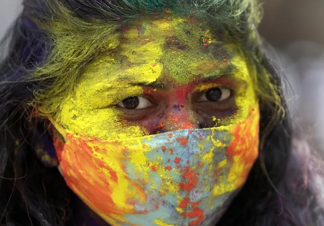 An Indian woman smeared in colors looks on during Holi festival in Mumbai, India, Monday, March 29, 2021. (Photo by Rajanish Kakade/AP Photo)