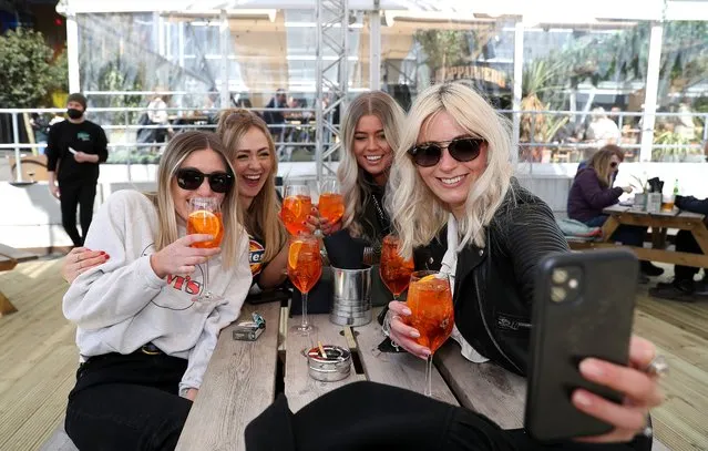 (L-R) Sara Barnes, Katie Davies, Amber Harrison and Georgia Noon take a selfie as they enjoy a drink at the Escape to Freight Island bar in Depot Island, Manchester on Monday April 12, 2021, as England takes another step back towards normality with the further easing of lockdown restrictions. (Photo by Martin Rickett/PA Images via Getty Images)