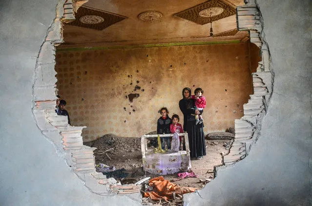 A women and her children stand in the ruins of battle-damaged house in the Kurdish town of Silopi, in southeastern Turkey, near the border with Iraq on January 19, 2016. Turkey is waging an all-out offensive against the separatist Kurdistan Workers' Party (PKK), with military operations backed by curfews aimed at flushing out rebels from several southeastern urban centres. (Photo by Ilyas Akengin/AFP Photo)
