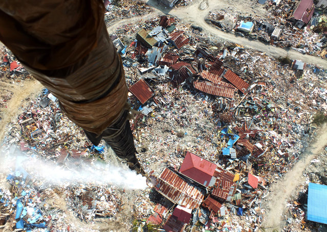 This picture taken from a helicopter on October 18, 2018 shows disinfectant being released over an area, affected by liquefaction due to the September 28 earthquake and where thousands are still feared buried, in an attempt to sterilise it in Palu. The World Bank on October 14 announced funding of up to $1 billion for Indonesia after it was rocked by a string of recent disasters, including a deadly earthquake-tsunami that killed thousands. (Photo by Muhammad Rifki/AFP Photo)