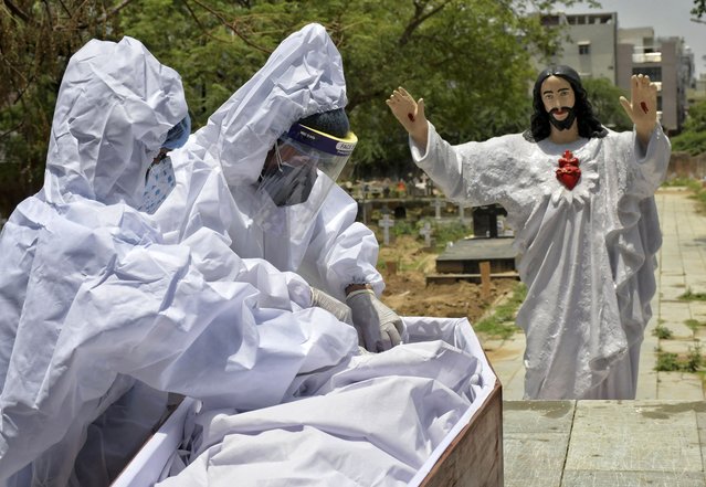 Body of a COVID-19 victim is prepared for burial at a Christian cemetery in New Delhi, India, Saturday, May 29, 2021. India's death toll is the third-highest reported in the world after the U.S. and Brazil. (Photo by Ishant Chauhan/AP Photo)
