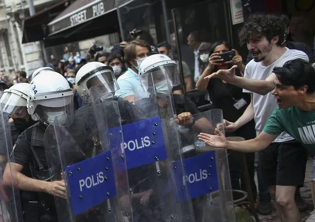 Activists, right, scream to police officers in riot gear moving to disperse the crowds that tried to stage a pride event in central Istanbul, Saturday, June 26, 2021. Police used tear gas and rubber bullets to disperse the crowds and detained dozens of LGTBI activists as hundreds defied a ban and tried to stage a gay pride event. (Photo by Emrah Gurel/AP Photo)