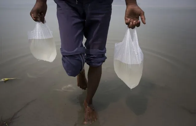 A vegetable seller carries water from river Brahmaputra before spraying them on vegetables on World Water Day in Gauhati, India, Sunday, March 22, 2015. (Photo by Anupam Nath/AP Photo)