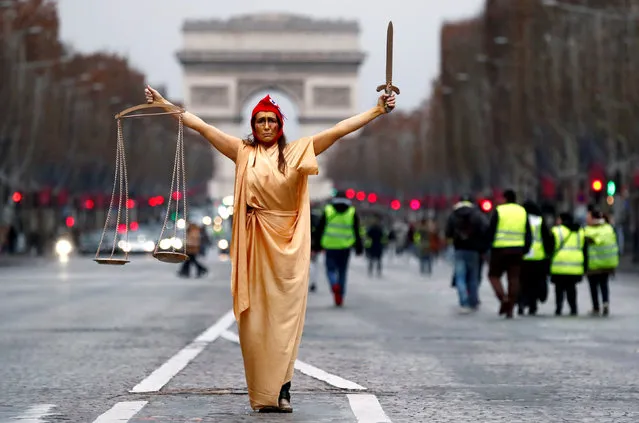 A woman dressed as Justice and French republic symbol “Marianne” poses during a demonstration by the “yellow vests” movement on the Champs Elysees near the Arc de Triomphe in Paris, France, December 22, 2018. (Photo by Christian Hartmann/Reuters)