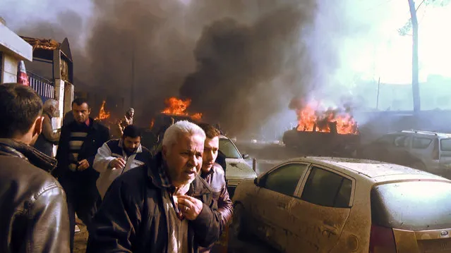 An image grab taken from an AFPTV video released on January 7, 2017 shows people gathering amidst the debris at the site of a car bomb attack in the rebel-held town of Azaz in northern Syria. According to the Syrian Observatory for Human Rights, at least 43 people were killed and dozens injured in the blast that ripped through the town near the Turkish border. (Photo by AFP Photo/Stringer)