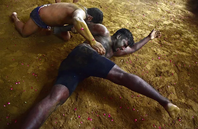 Wrestlers take part in a bout of traditional wrestling at the Loknath Vyayamsala wrestling club to mark the Nag Panchami festival in Allahabad on August 13, 2021. (Photo by Sanjay Kanojia/AFP Photo)