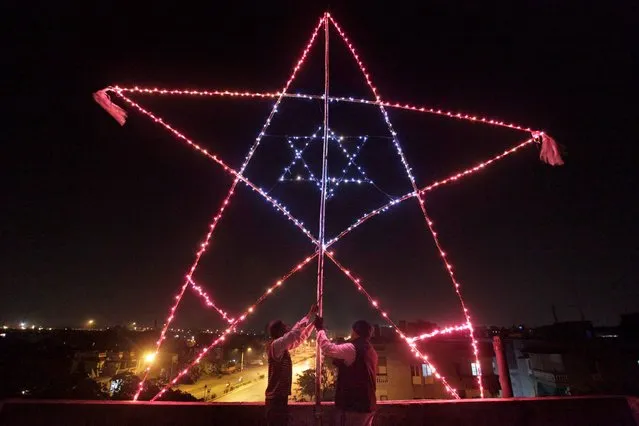 In this Monday, December 23, 2013 photo, Indian Christians illuminate a  23 feet (7 meter) huge star on the terrace of their residential building in Ahmadabad, India.  Although Christians comprise only two percent of the Indian population but Christmas is a national holiday and is observed across the country as an occasion to celebrate. (Photo by Ajit Solanki/AP Photo)