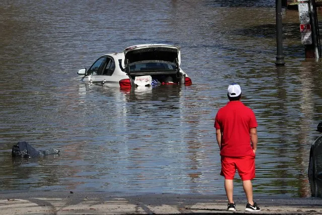 A man looks at a car in floodwaters after remnants of Ida brought drenching rain, flash floods and tornadoes to parts of the Northeast in Mamaroneck, New York, September 2, 2021. (Photo by Mike Segar/Reuters)