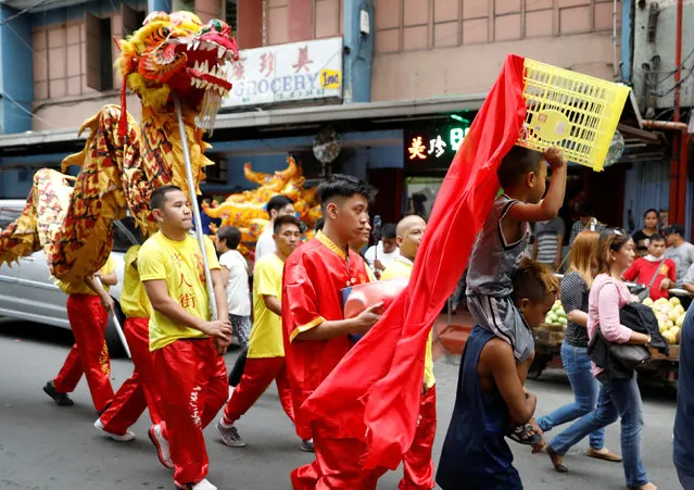 Performers walk along a street next to children using makeshift dragon dancer's costume on the eve of Lunar New Year in Manila's Chinatown, Philippines January 27, 2017. (Photo by Erik De Castro/Reuters)