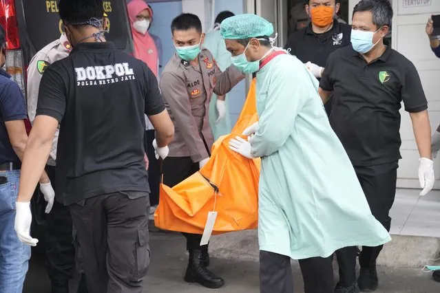 Officers load a body bag containing the body of a victim of a prison fire to be transferred to the national police hospital for identification at the local hospital in Tangerang on the outskirts of Jakarta, Indonesia, Wednesday, September 8, 2021. A massive fire raged through the overcrowded prison early Wednesday, killing a number of inmates. (Photo by Dita Alangkara/AP Photo)