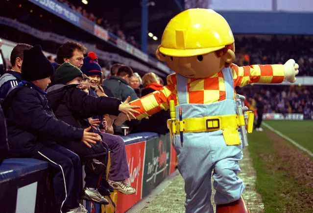 A performer dressed up as Bob The Builder greets young football fans at a football match between Queens Park Rangers and Nottingham Forest at Loftus Road, London, on December 16, 2000. (Photo by Action Images via Reuyers)