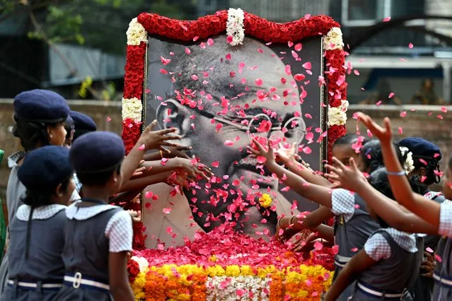 Indian school children throws rose flower petals over a portrait of Mahatma Gandhi to pay their tribute on the death anniversary of the Indian founding father, in Chennai on January 30, 2024. The death anniversary of Gandhi, who is widely known in India as Bapu (father), is also observed as Martyrs' Day in the country. (Photo by R.Satish Babu/AFP Photo)