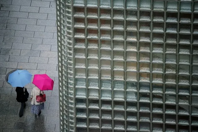 People walk in the rain Wednesday, October 13, 2021, in Tokyo. (Photo by Eugene Hoshiko/AP Photo)