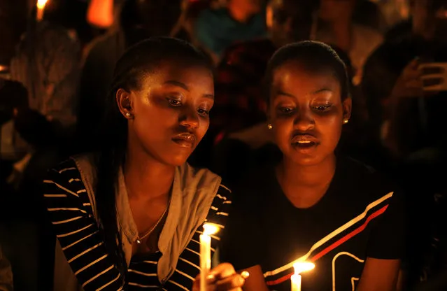 Rwandan women sitting in the stands, hold candles as part of a candlelit vigil during the memorial service held at Amahoro stadium in the capital Kigali, Rwanda, Sunday, April 7, 2019. Rwanda is commemorating the 25th anniversary of when the country descended into an orgy of violence in which some 800,000 Tutsis and moderate Hutus were massacred by the majority Hutu population over a 100-day period in what was the worst genocide in recent history. (Photo by Ben Curtis/AP Photo)