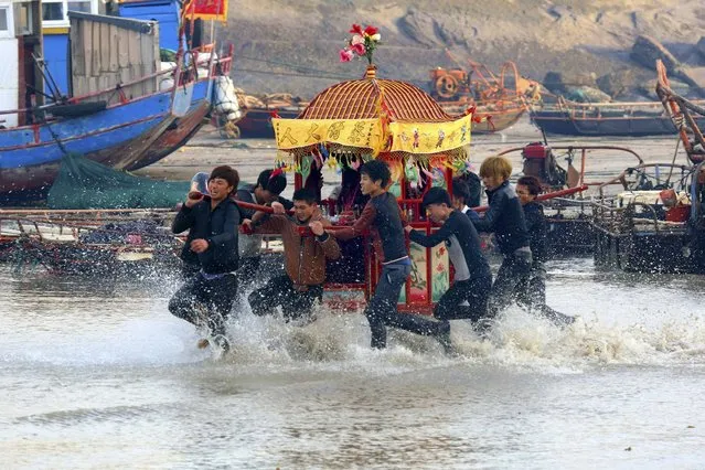 Villagers run in sea water as they carry a sedan chair holding their gods during an annual folk performance known as “sea rush” to celebrate the Lantern Festival in Nanri Island of Putian, Fujian province, on February 18, 2014. (Photo by Reuters/Stringer)