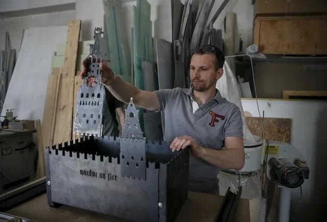 A Ukrainian artist assembles a barbecue grill in the shape of Moscow's Kremlin at his workshop in Kiev May 14, 2015. A group of Ukrainian artists are working on a project entitled “Mordor on Fire” where they create grills that are sold, and some donated to Ukrainian soldiers in the eastern conflict zone. (Photo by Gleb Garanich/Reuters)