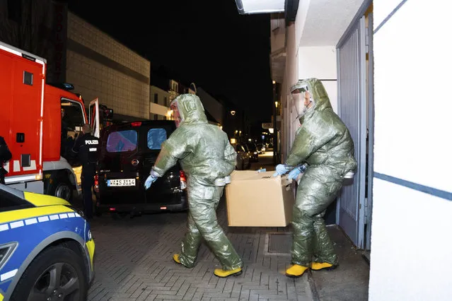 Men in protective suits carry a cardboard box out of a house in Castrop-Rauxel during an anti-terror operation on Sunday, January 8, 2023. German investigators are searching two garages used by an Iranian man arrested on suspicion that he could be planning an attack with deadly chemicals. The 32-year-old and his 25-year-old brother were detained on Saturday night in Castrop-Rauxel, in western Germany, following a tip from U.S. security officials. (Photo by 7aktuell.de, Marc Gruber/dpa via AP Photo)