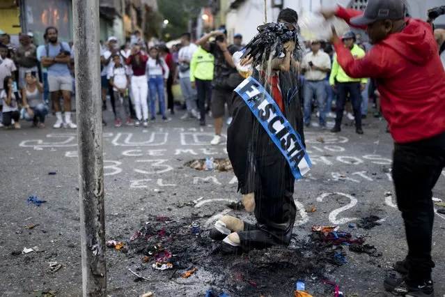 A resident pours gasoline over an effigy wearing a sash with the Spanish word for fascist, as part of The Burning of the Judases Easter Sunday tradition, in Caracas, Venezuela, March 31, 2024. Venezuelans came out to watch the burning of Judas effigies, the apostle who betrayed Jesus Christ, but also effigies of personalities who represent evil and corruption. (Photo by Ariana Cubillos/AP Photo)