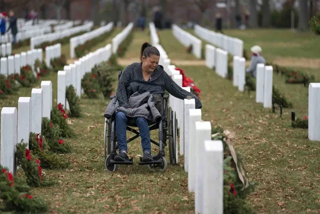 Patricia Berkey grieves at the headstone of her late husband William Brian Berkey after laying a holiday wreath in Arlington National Cemetery during Wreaths Across America Day in Arlington, Va., Saturday, December 18, 2021. (Photo by Gemunu Amarasinghe/AP Photo)