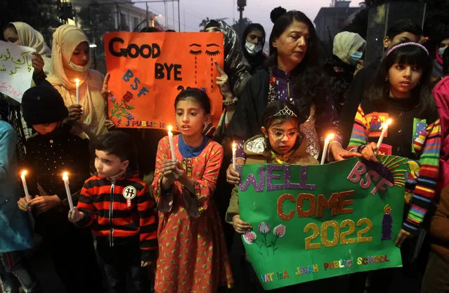 Students hold candles during a rally to pray for peace in year 2022 on New Year's Eve in Lahore, Pakistan, 31 December 2021. (Photo by Rahat Dar/EPA/EFE)