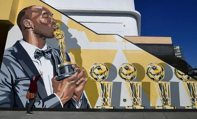 A man touches a mural by artist Bryan Peterson of the late Kobe Bryant depicted kissing his Academy Award on January 25, 2022 in Hollywood, California, a day before the two-year death anniversary of the former Los Angeles Lakers star. Lakers star Kobe Bryant died with his daughter Gianna in a tragic helicopter crash which killed nine people on January 27, 2020. (Photo by Frederic J. Brown/AFP Photo)