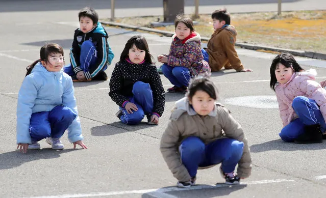 Elementary school students crouch during an evacuation drill in Oga, Aomori prefecture, northern Japan Friday, March 17, 2017. For the first time the Japanese government held an emergency drill aimed at protecting its citizens in case a ballistic missile is launched toward Japan. Over 100 residents and schoolchildren of the coastal city of Oga in Northern Japan participated in the Friday drill which lasted about half an hour. (Photo by Jun Hirata/Kyodo News via AP Photo)