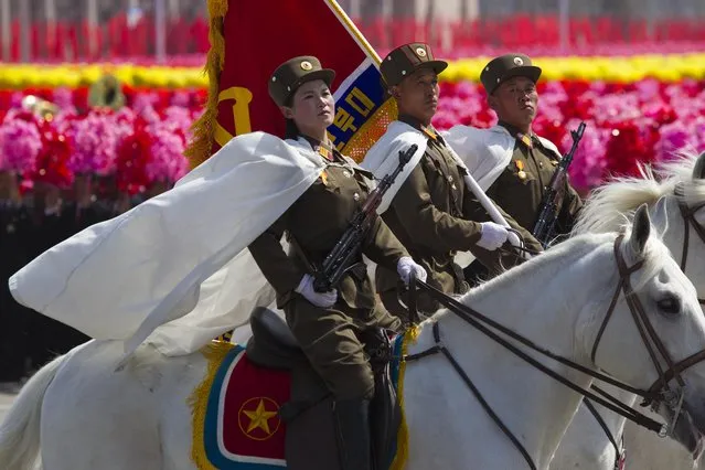 North Korean soldiers ride by on horses in front of flower waving civilians during a mass military parade in Pyongyang's Kim Il Sung Square to celebrate 100 years since the birth of the late North Korean founder Kim Il Sung on Sunday, April 15, 2012. (Photo by David Guttenfelder/AP Photo)