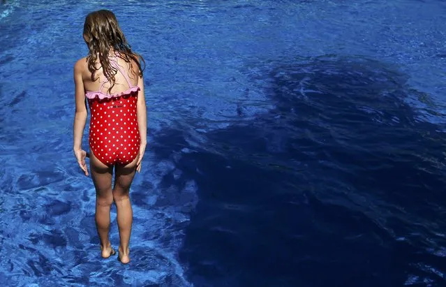 A girl jumps into the water to cool off from the heat at “Grugabad” open-air swimming pool on a hot summer day in Essen, Germany, June 30, 2015. A widespread, long-lasting heat wave will spread across much of France, U.K., Belgium, the Netherlands and western Germany with forecast highs on Wednesday reaching 35 degrees Celsius (95 degrees Fahrenheit). (Photo by Ina Fassbender/Reuters)